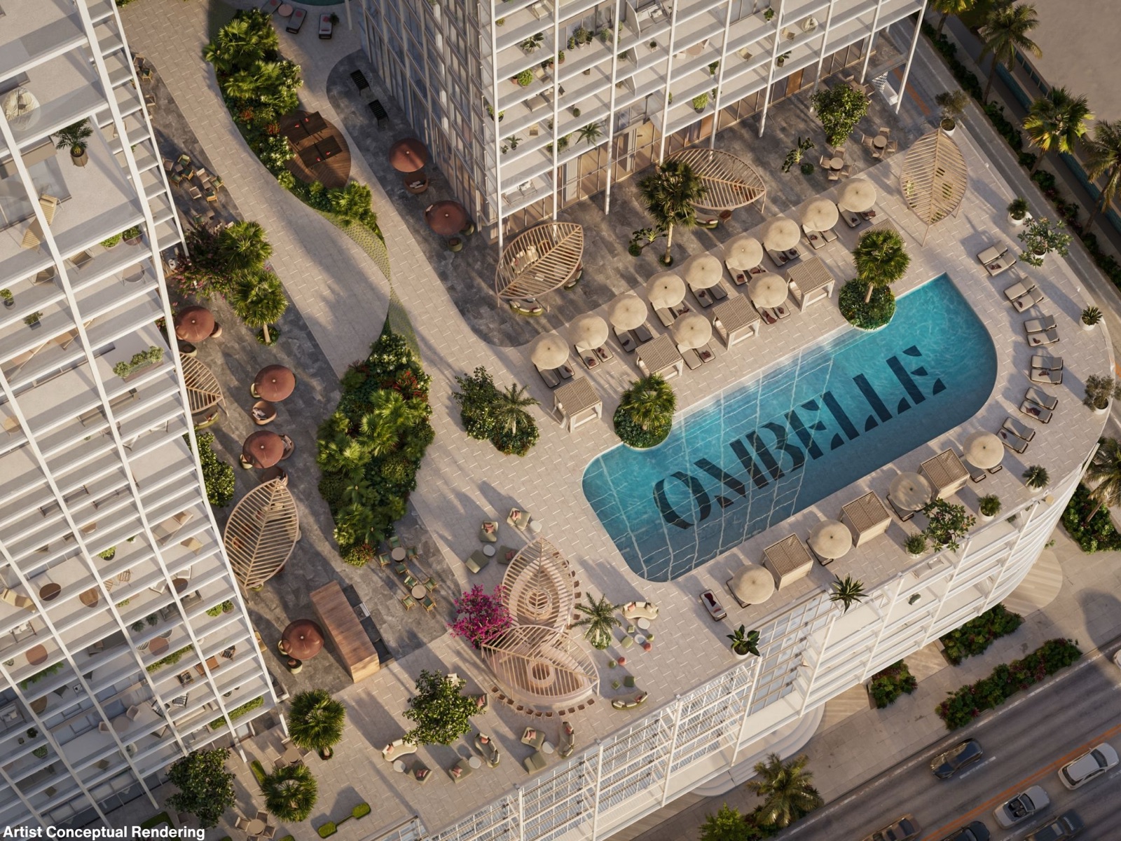 Aerial view of the Ombelle-branded pool on the Sky Deck — a turquoise pool spelling OMBELLE across its floor, ringed by chaise lounges, umbrellas, and wicker cabanas between the two towers.